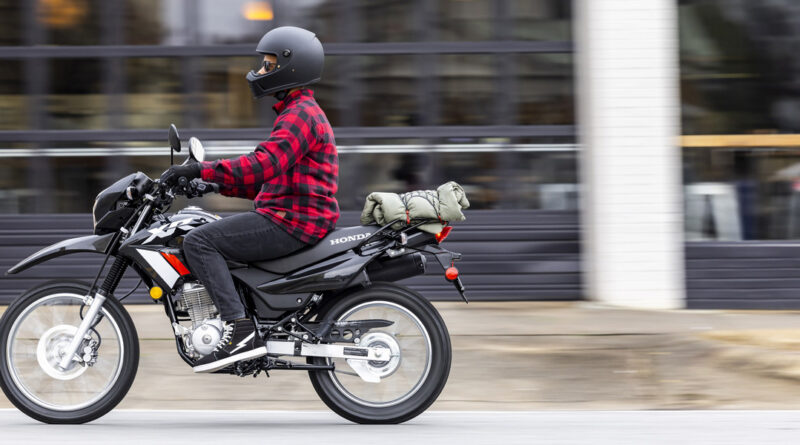 A rider and in-motion XR150L in focus while the background is blurred