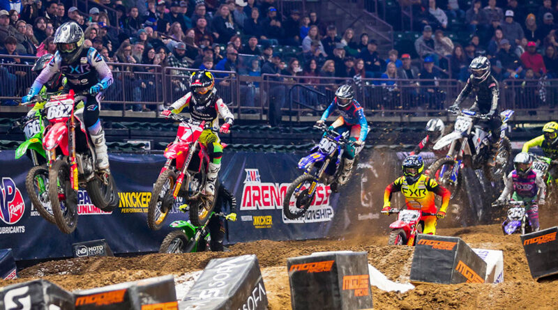 Arenacross riders hitting a series of jumps as an arena full of people looks on