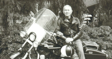 Black and white photo of Roger Hull posing for a photo while sitting on his street motorcycle