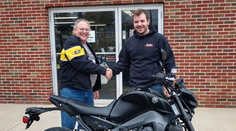 Mark Krieger standing outside and shaking hands with a man at Mid-Ohio store while receiving his Yamaha MT-09 from winning the AMA Member Sweepstakes.